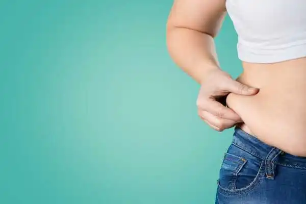 Image of woman pinching her love handles to show weight gain Wales