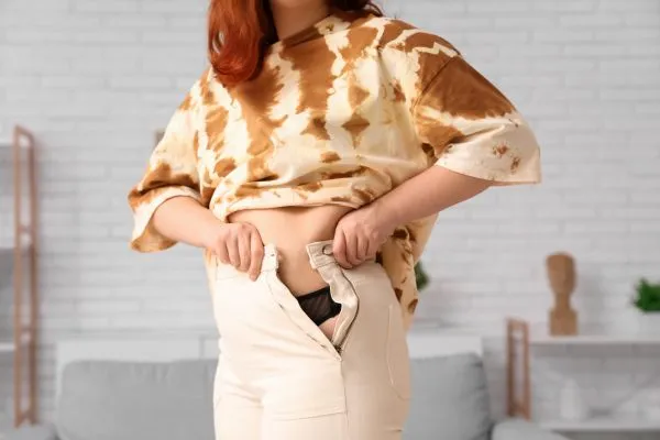 Image of woman trying to do her trousers up after pregnancy weight gain Wales